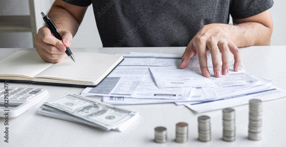 Two adults at a kitchen table reviewing a handwritten budget and laptop spreadsheet together.