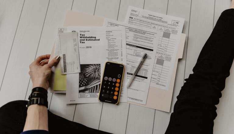 A family at a kitchen table sorting tax documents with a laptop, paper forms, and a cup of coffee.